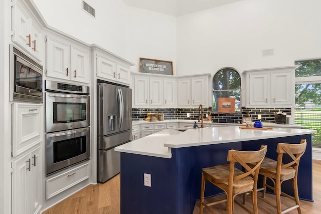 2623 Old S Dr, Richmond, TX 77406 - kitchen with stainless steel appliances, a breakfast bar, light countertops, light wood-style flooring, and backsplash