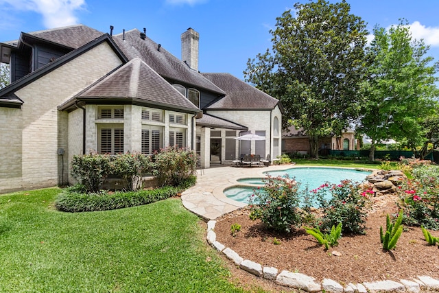 2623 Old S Dr, Richmond, TX 77406 - back of house featuring a patio area, roof with shingles, a chimney, a pool with connected hot tub, and stone siding