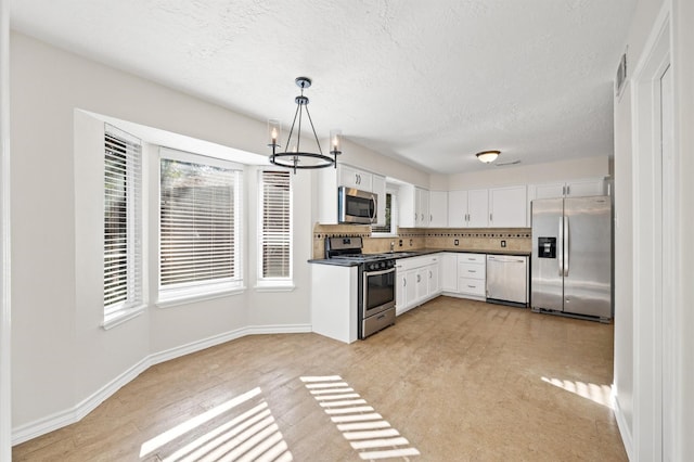 16522 Courtland Cir, Spring, TX 77379 - kitchen featuring appliances with stainless steel finishes, a chandelier, white cabinets, decorative backsplash, and dark countertops