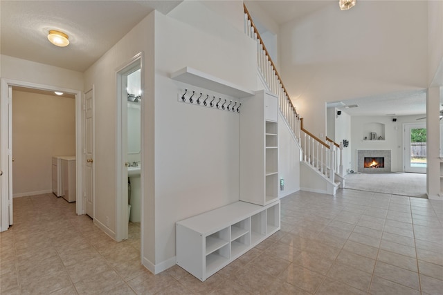 19126 Edens Dawn Dr, Tomball, TX 77375 - mudroom with light tile patterned floors, a warm lit fireplace, baseboards, and washer / clothes dryer