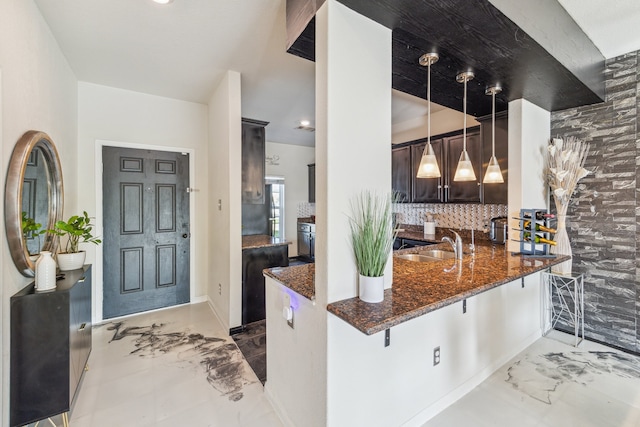 15203 Albert Oak Dr, Humble, TX 77396 - kitchen with marble finish floors, dark stone counters, backsplash, a sink, and hanging light fixtures