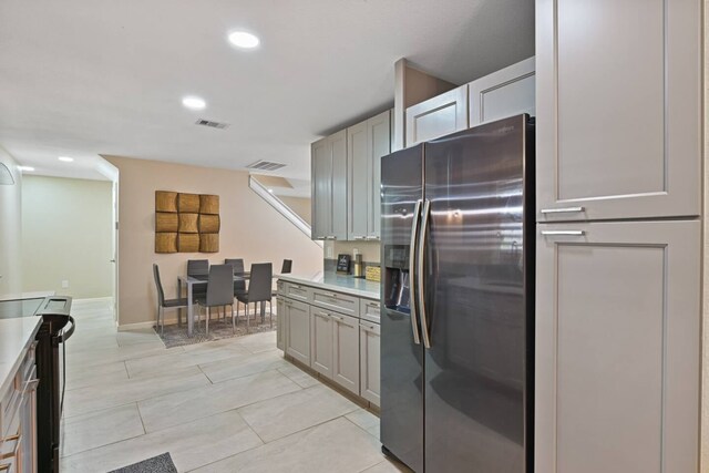 2402 Pine St, Galveston, TX 77551 - kitchen with stainless steel refrigerator with ice dispenser, light countertops, recessed lighting, gray cabinets, and baseboards