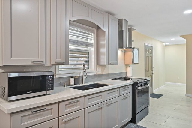 2402 Pine St, Galveston, TX 77551 - kitchen featuring stainless steel appliances, wall chimney exhaust hood, a sink, baseboards, and light stone countertops