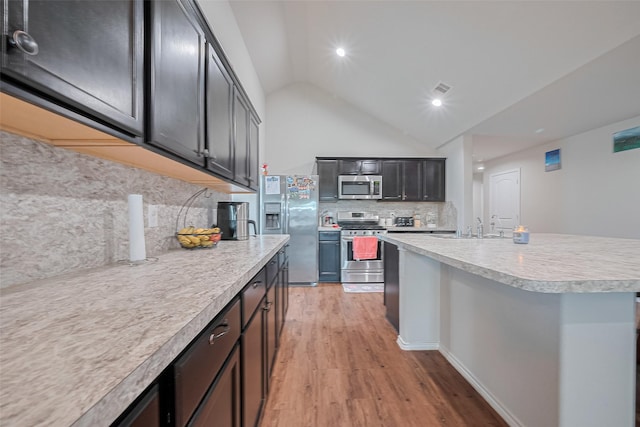 21018 Whitehaven Bluff Trl, Katy, TX 77449 - kitchen featuring stainless steel appliances, backsplash, vaulted ceiling, light wood-style flooring, and light countertops