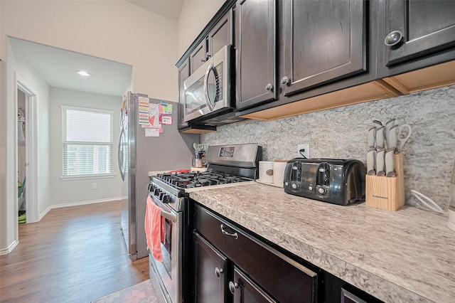 21018 Whitehaven Bluff Trl, Katy, TX 77449 - kitchen featuring appliances with stainless steel finishes, light countertops, light wood finished floors, backsplash, and baseboards