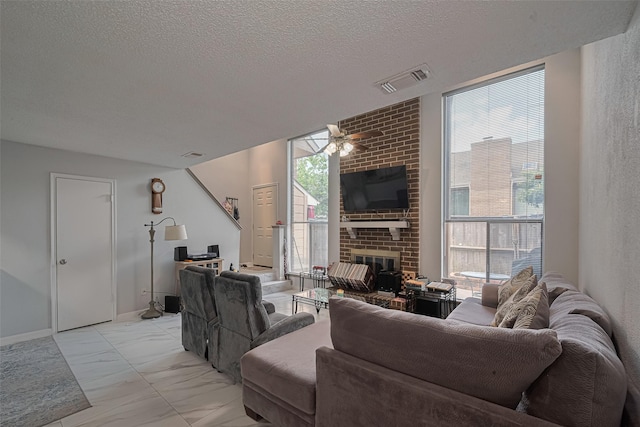 13798 Hollowgreen Dr Unit 305, Houston, TX 77082 - living room with plenty of natural light, a ceiling fan, light marble finish flooring, a brick fireplace, and a textured ceiling