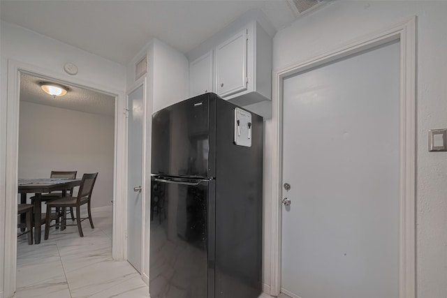 13798 Hollowgreen Dr Unit 305, Houston, TX 77082 - kitchen featuring freestanding refrigerator, light marble finish flooring, and white cabinets
