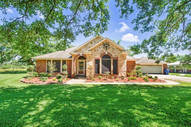 120 Brazos River Rd Unit 400, Freeport, TX 77541 - view of front of home with a front yard, an attached garage, concrete driveway, stone siding, and brick siding