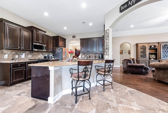 5923 Vinland Shores Ct, Spring, TX 77379 - kitchen featuring arched walkways, stainless steel appliances, open floor plan, a kitchen breakfast bar, and recessed lighting