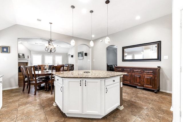 2911 Fair Chase Dr, Katy, TX 77494 - kitchen featuring arched walkways, vaulted ceiling, decorative light fixtures, white cabinetry, and a kitchen island