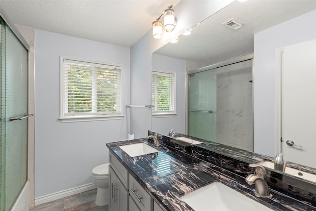15119 Plaza Libre Dr, Houston, TX 77083 - bathroom featuring double vanity, wood finished floors, toilet, a textured ceiling, and baseboards