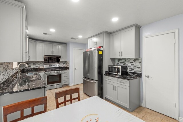 15119 Plaza Libre Dr, Houston, TX 77083 - kitchen with stainless steel appliances, gray cabinetry, a sink, tasteful backsplash, and dark stone countertops