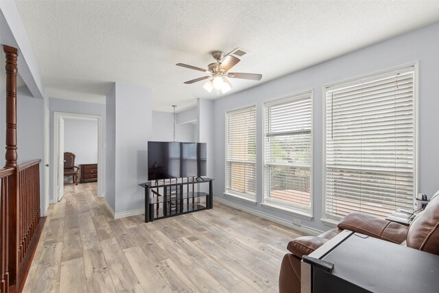 15119 Plaza Libre Dr, Houston, TX 77083 - living room with a ceiling fan, light wood-style floors, a textured ceiling, and baseboards