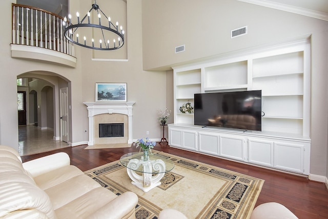 7111 Morrow Ct, Sugar Land, TX 77479 - living room with dark wood-style flooring, arched walkways, high vaulted ceiling, a chandelier, and a tile fireplace