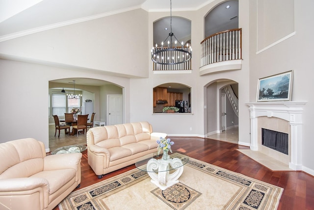 7111 Morrow Ct, Sugar Land, TX 77479 - living room with arched walkways, a chandelier, wood finished floors, a tiled fireplace, and crown molding
