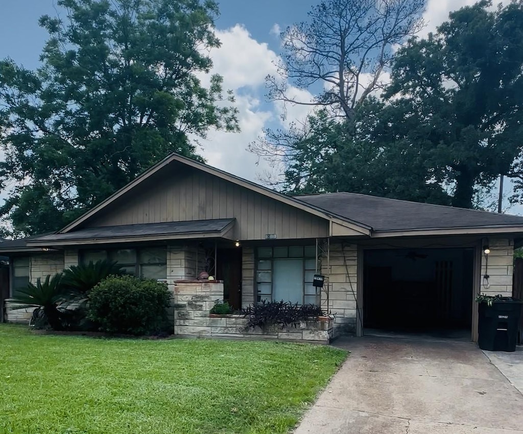 10419 Rockaway Dr, Houston, TX 77016 - view of front of home featuring concrete driveway, an attached garage, a front lawn, and stone siding