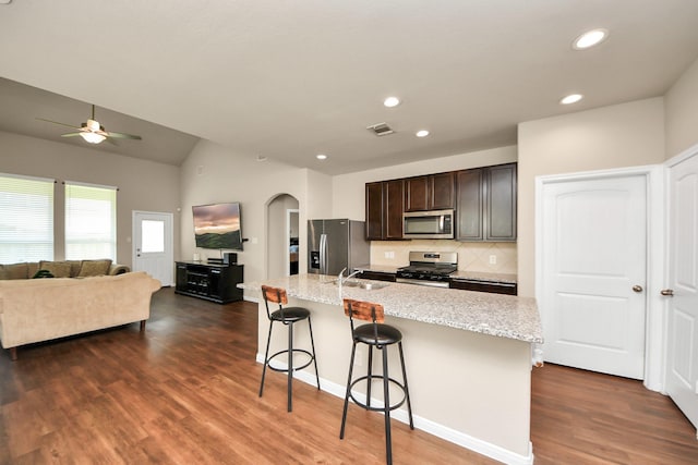 24739 Lorenzo Glaze Trl, Katy, TX 77493 - kitchen featuring stainless steel appliances, a sink, arched walkways, open floor plan, and a kitchen breakfast bar