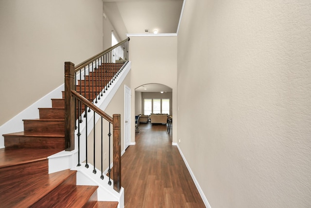 24739 Lorenzo Glaze Trl, Katy, TX 77493 - staircase featuring arched walkways, wood finished floors, baseboards, and a high ceiling