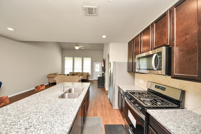 24739 Lorenzo Glaze Trl, Katy, TX 77493 - kitchen featuring appliances with stainless steel finishes, light wood-style flooring, a sink, tasteful backsplash, and a ceiling fan