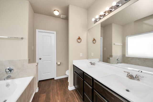 24739 Lorenzo Glaze Trl, Katy, TX 77493 - bathroom featuring double vanity, a garden tub, toilet, wood finished floors, and baseboards