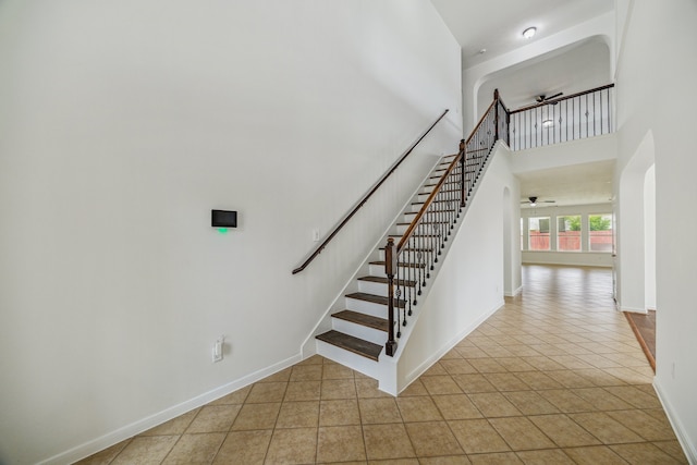 26402 Larkspur Ridge Dr, Katy, TX 77494 - staircase featuring ceiling fan, tile patterned floors, baseboards, a high ceiling, and arched walkways