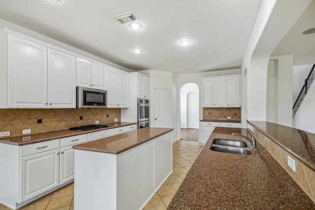 26402 Larkspur Ridge Dr, Katy, TX 77494 - kitchen with arched walkways, stainless steel appliances, a sink, decorative backsplash, and a kitchen island