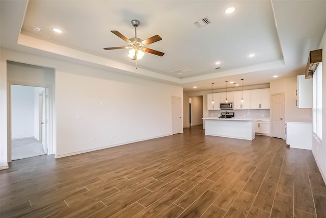 11514 Harmony Summit Trce, Richmond, TX 77406 - unfurnished living room with a raised ceiling, dark wood-style floors, ceiling fan, and recessed lighting