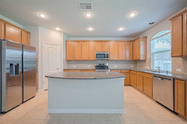 24523 Carlton Springs Ln, Katy, TX 77494 - kitchen featuring appliances with stainless steel finishes, a sink, stone countertops, a kitchen island, and light tile patterned floors