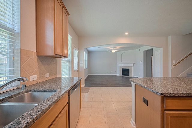 24523 Carlton Springs Ln, Katy, TX 77494 - kitchen with stainless steel dishwasher, a sink, ceiling fan, light tile patterned floors, and a tiled fireplace