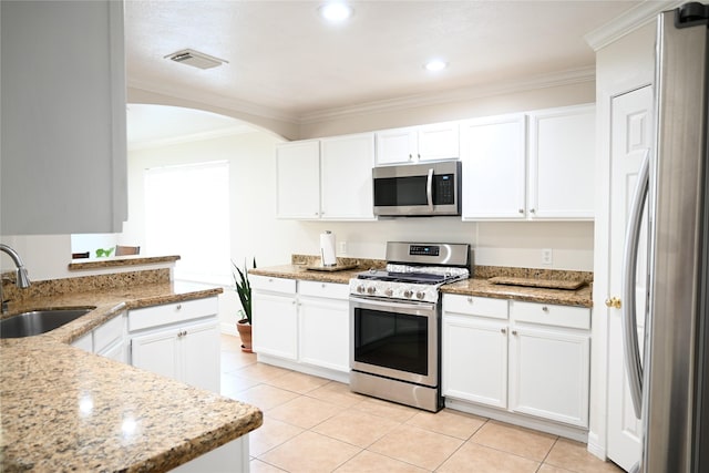 5902 Camron Point Cir, Katy, TX 77449 - kitchen with appliances with stainless steel finishes, a sink, crown molding, arched walkways, and light tile patterned flooring