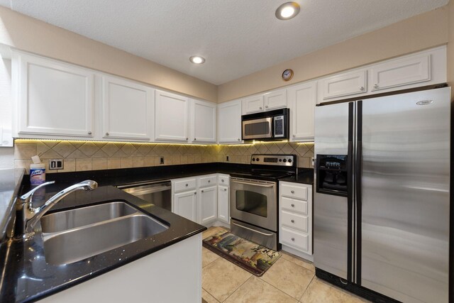 2611 Grants Lake Blvd Unit 222, Sugar Land, TX 77479 - kitchen with stainless steel appliances, a sink, white cabinetry, light tile patterned flooring, and decorative backsplash