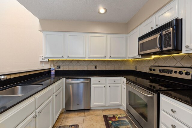 2611 Grants Lake Blvd Unit 222, Sugar Land, TX 77479 - kitchen featuring appliances with stainless steel finishes, tasteful backsplash, white cabinets, a textured ceiling, and light tile patterned floors
