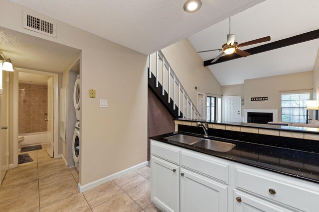 2611 Grants Lake Blvd Unit 222, Sugar Land, TX 77479 - kitchen featuring stacked washer / dryer, a sink, ceiling fan, vaulted ceiling, and light tile patterned flooring