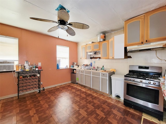 418 Bishop St, Houston, TX 77009 - kitchen with stainless steel range with gas cooktop, under cabinet range hood, ceiling fan, light countertops, and glass insert cabinets