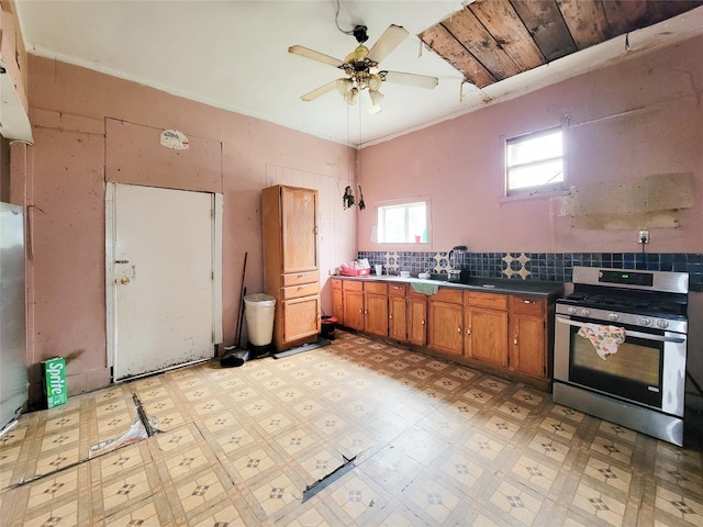 418 Bishop St, Houston, TX 77009 - kitchen with stainless steel gas stove, brown cabinetry, light floors, ceiling fan, and decorative backsplash