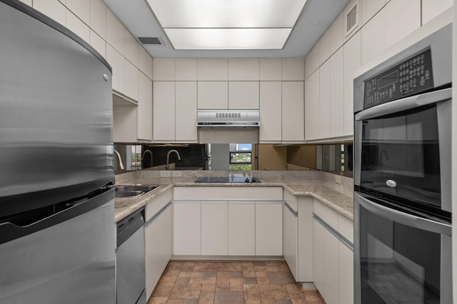 5100 San Felipe St Unit 98, Houston, TX 77056 - kitchen with appliances with stainless steel finishes, range hood, stone finish flooring, and white cabinets