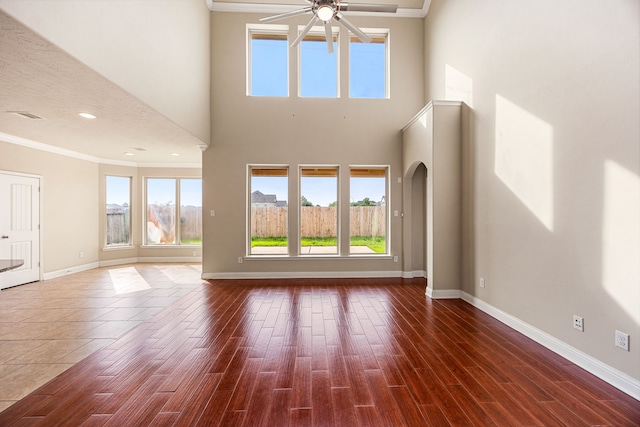 20522 Saddleback Chase Ln, Cypress, TX 77433 - unfurnished living room featuring ornamental molding, a ceiling fan, baseboards, plenty of natural light, and a towering ceiling