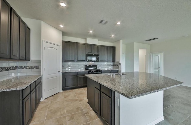 28430 Buffalo Fork Ln, Katy, TX 77494 - kitchen with black appliances, a sink, backsplash, a center island with sink, and a textured ceiling