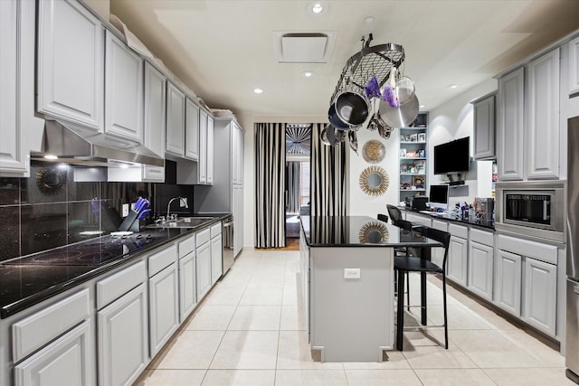 511 S Post Oak Ln Unit 6D, Houston, TX 77056 - kitchen featuring stainless steel appliances, a center island, light tile patterned floors, backsplash, and a sink