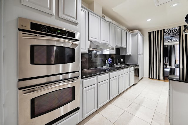 511 S Post Oak Ln Unit 6D, Houston, TX 77056 - kitchen with stainless steel appliances, light tile patterned floors, a sink, dark countertops, and tasteful backsplash