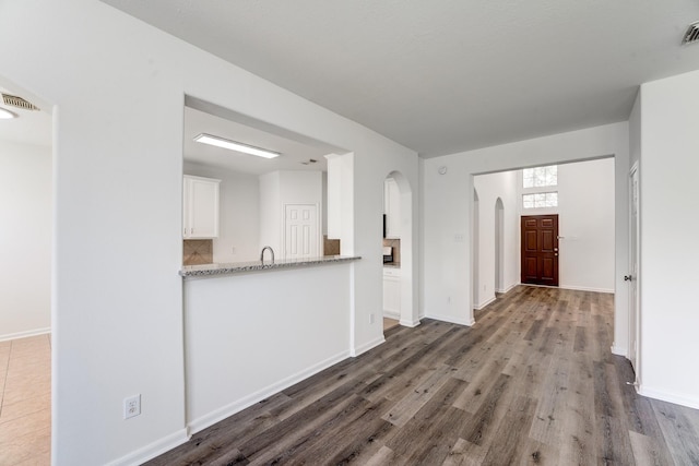 16906 Shoal Park Dr, Cypress, TX 77429 - unfurnished living room with wood finished floors, arched walkways, baseboards, and a sink