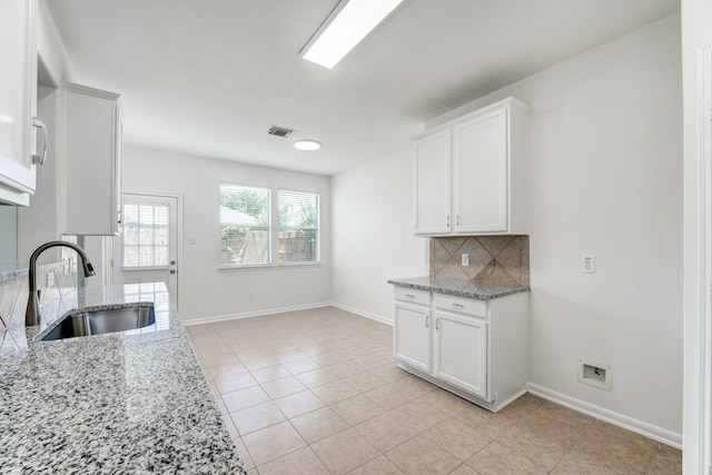 16906 Shoal Park Dr, Cypress, TX 77429 - kitchen featuring a sink, decorative backsplash, light stone countertops, white cabinets, and baseboards