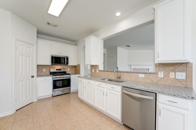 16906 Shoal Park Dr, Cypress, TX 77429 - kitchen with stainless steel appliances, a sink, decorative backsplash, arched walkways, and white cabinets