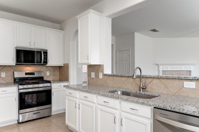 16906 Shoal Park Dr, Cypress, TX 77429 - kitchen featuring stainless steel appliances, a sink, light stone counters, white cabinetry, and decorative backsplash