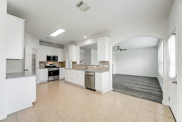 16906 Shoal Park Dr, Cypress, TX 77429 - kitchen with stainless steel appliances, a sink, ceiling fan, arched walkways, and backsplash