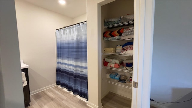 21138 Titian Dr, Magnolia, TX 77355 - full bath featuring wood finished floors, vanity, baseboards, and a shower with shower curtain