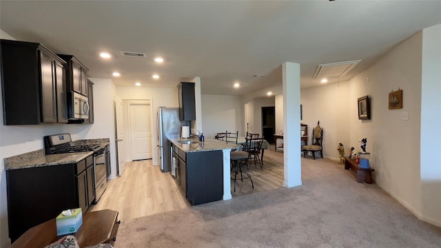 21138 Titian Dr, Magnolia, TX 77355 - kitchen with stainless steel appliances, a breakfast bar, light stone counters, a sink, and recessed lighting