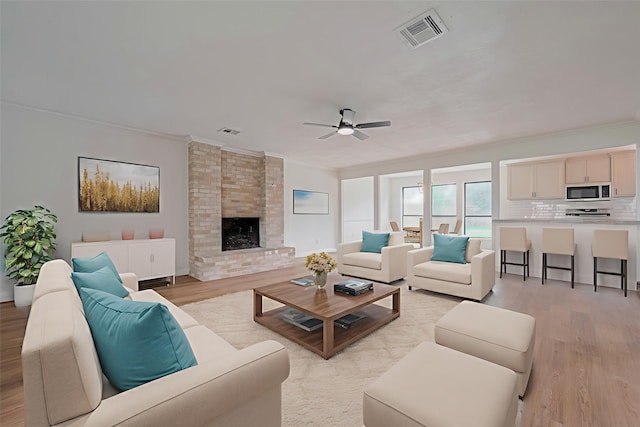 8014 Wray Ct, Houston, TX 77088 - living room featuring light wood finished floors, crown molding, a ceiling fan, and a brick fireplace