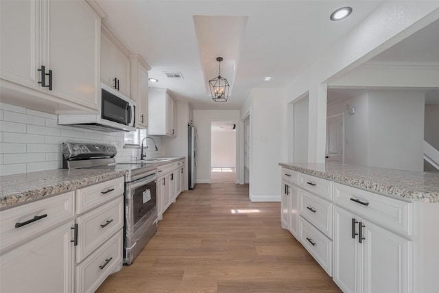 8014 Wray Ct, Houston, TX 77088 - kitchen featuring appliances with stainless steel finishes, a sink, decorative backsplash, light wood-style flooring, and baseboards