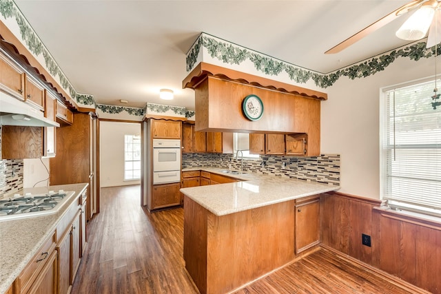 6310 Ash Oak Dr, Houston, TX 77091 - kitchen featuring white appliances, a warming drawer, brown cabinetry, a peninsula, and wainscoting